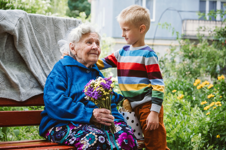 A young boy giving an elderly woman flowers